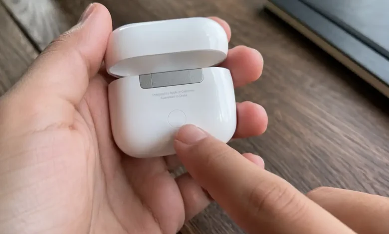 How to Reset AirPods (All Models) in Under 2 Minutes 1 hand holding open AirPods case showing setup button for how to reset AirPods